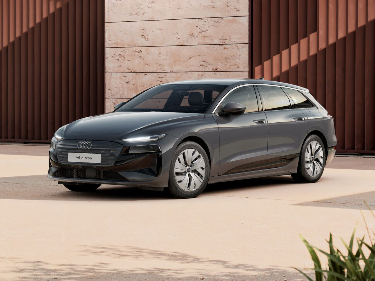 Audi A6 Avant e-tron in Grau in Frontansicht schräg geparkt vor moderner Architektur mit vertikalen Fassadenelementen