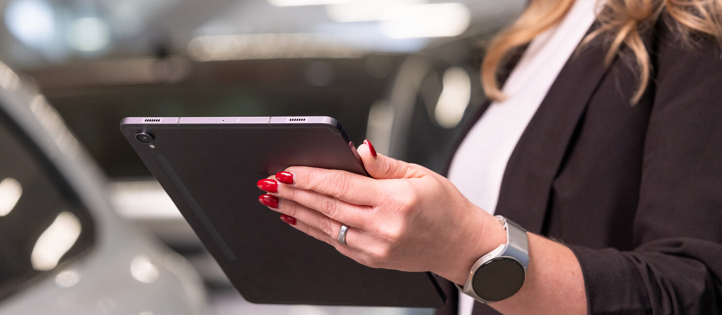 Frau hält ein Tablet in der Hand in der Fahrzeugausstellung des Auto Bach Autohauses