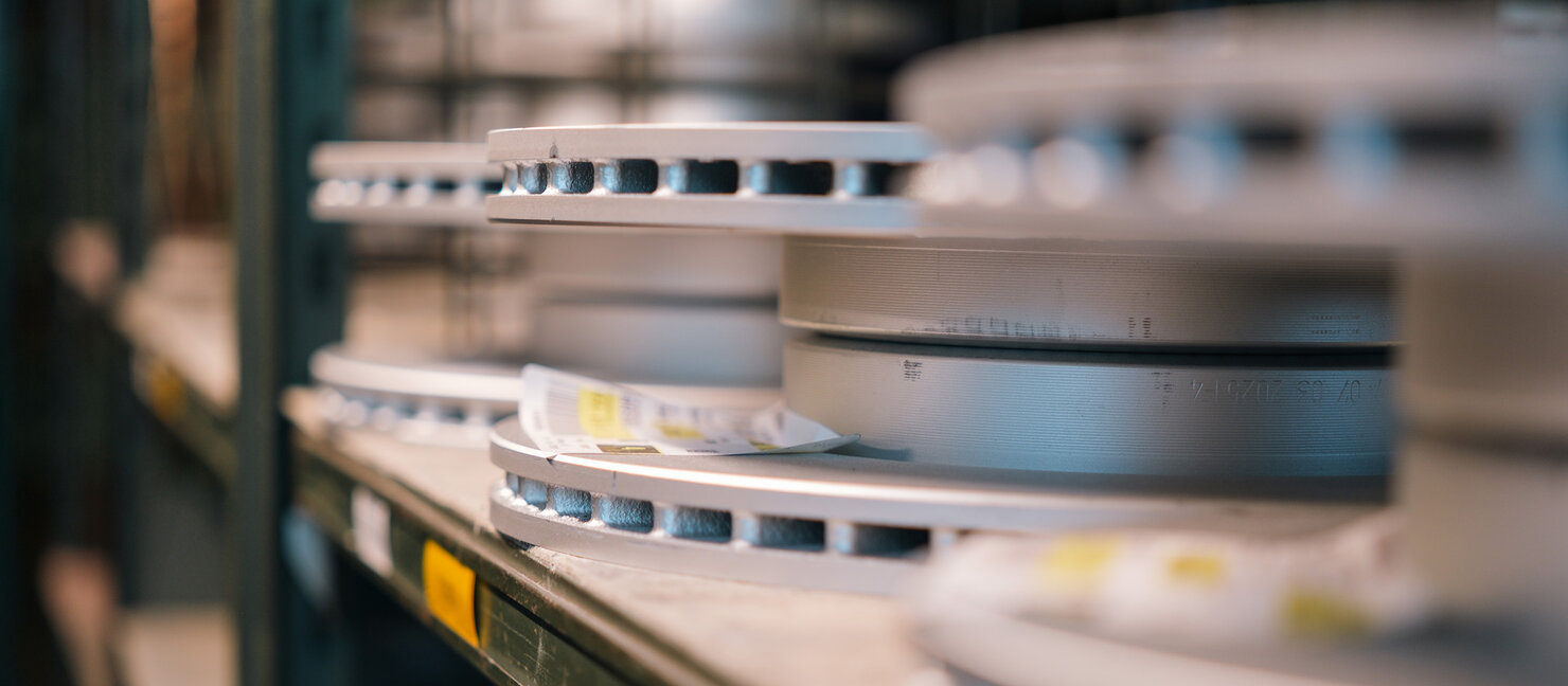 Gestapelte Bremsscheiben liegen ordentlich in einem Lagerregal eines Auto Bach Ersatzteillagers