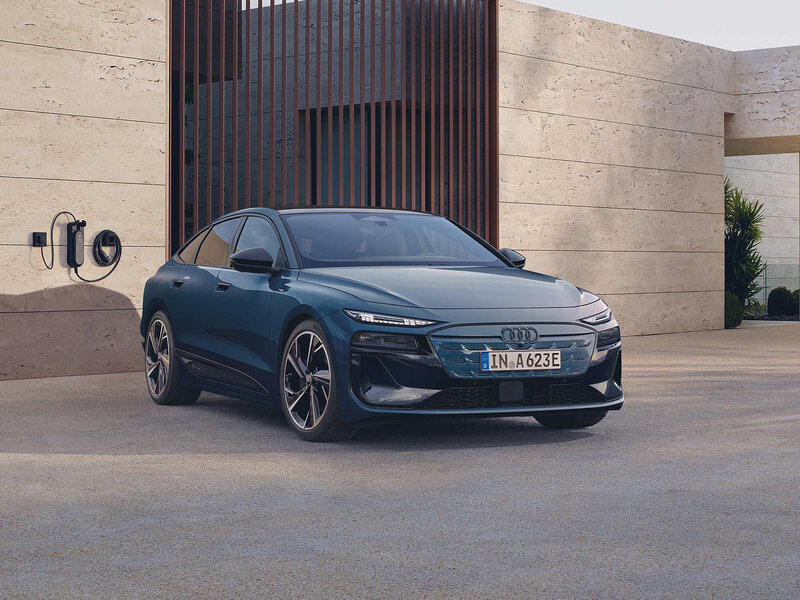 Audi A6 Sportback e-tron vor moderner Architektur mit flacher Coupé-Silhouette und aerodynamischem Elektro-Design