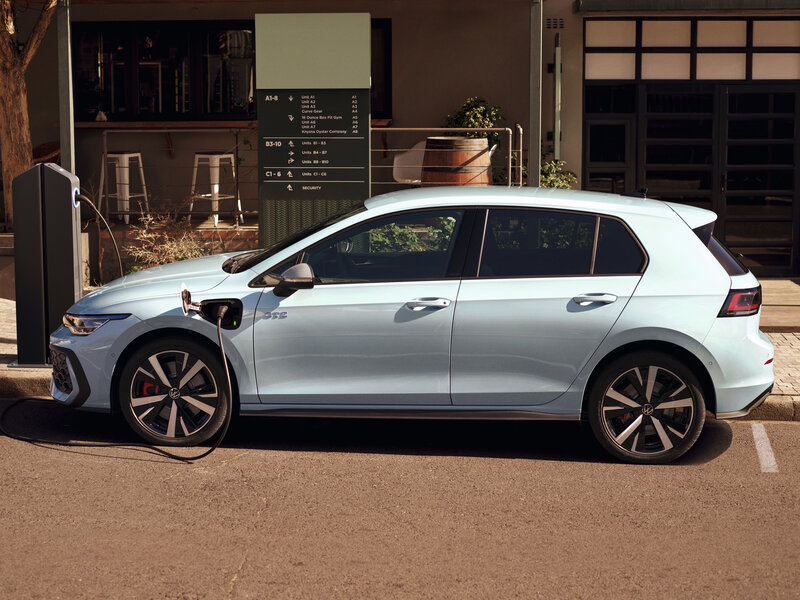 Ein Volkswagen Golf GTE steht am Straßenrand und ist über ein Ladekabel mit einer Ladestation verbunden.