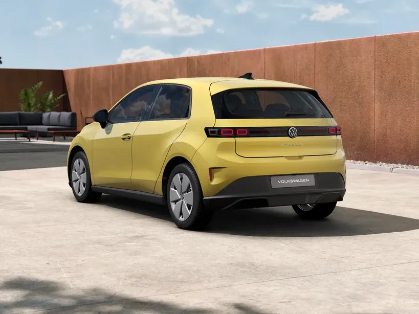 Volkswagen ID. Polo Life in Gelb in Heck-Dreiviertelansicht steht auf einer Betonfläche vor moderner Architektur unter blauem Himmel