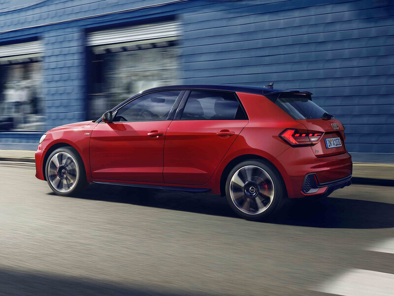 Roter Audi A1 Sportback in Fahrt von schräg hinten, dynamische Perspektive in städtischer Umgebung