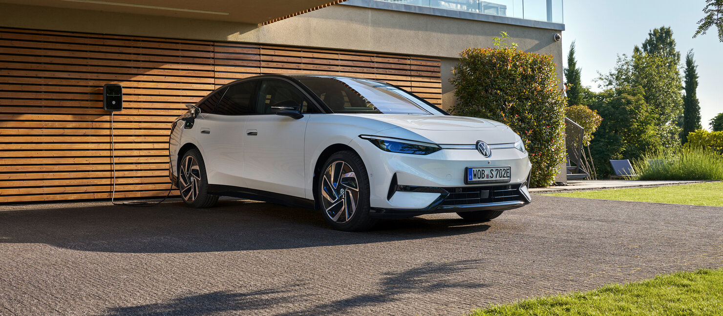 Weißer Volkswagen ID.7 vor moderner Holzfassade geparkt, Elektro-Limousine in ruhiger Wohnumgebung gezeigt