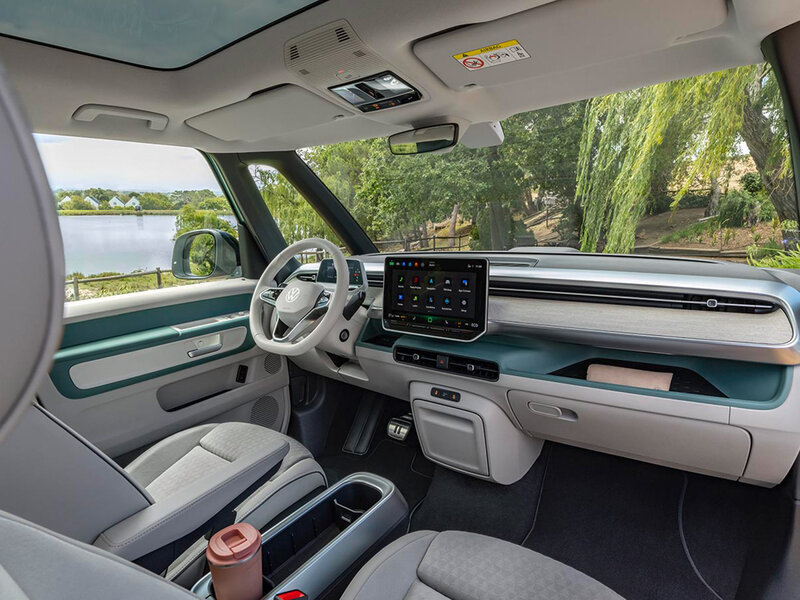 Innenraum des Volkswagen ID. Buzz mit hellem Armaturenbrett, Multifunktionslenkrad, zentralem Touchdisplay und großzügigem Platzangebot im Frontbereich.