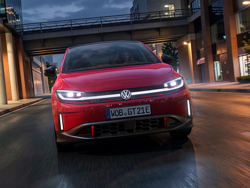Volkswagen ID. Polo GTI in Rot aus Frontperspektive auf urbaner Straße zwischen modernen Gebäuden bei Abenddämmerung
