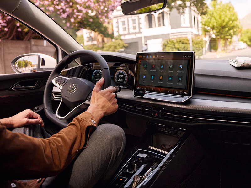 Innenansicht eines Volkswagen Golf mit digitalem Cockpit, zentralem Touchdisplay und Lenkrad aus der Fahrerperspektive.