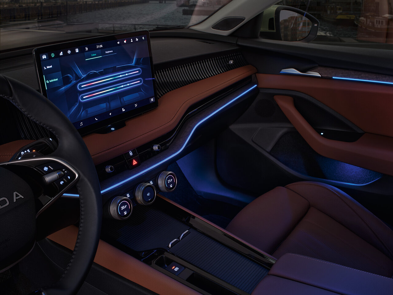 Innenraum des Škoda Superb mit braun-schwarzer Ausstattung, großem Infotainment-Display und blauer Ambientebeleuchtung bei Dämmerung