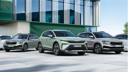 Drei Škoda SUV Modelle stehen vor modernem Autohausgebäude in Frontansicht auf Parkplatz