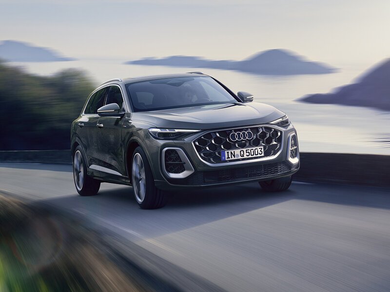 Audi Q5 in dynamischer Fahrszene entlang einer Küstenstraße mit kraftvollem SUV-Auftritt und markantem Singleframe-Grill