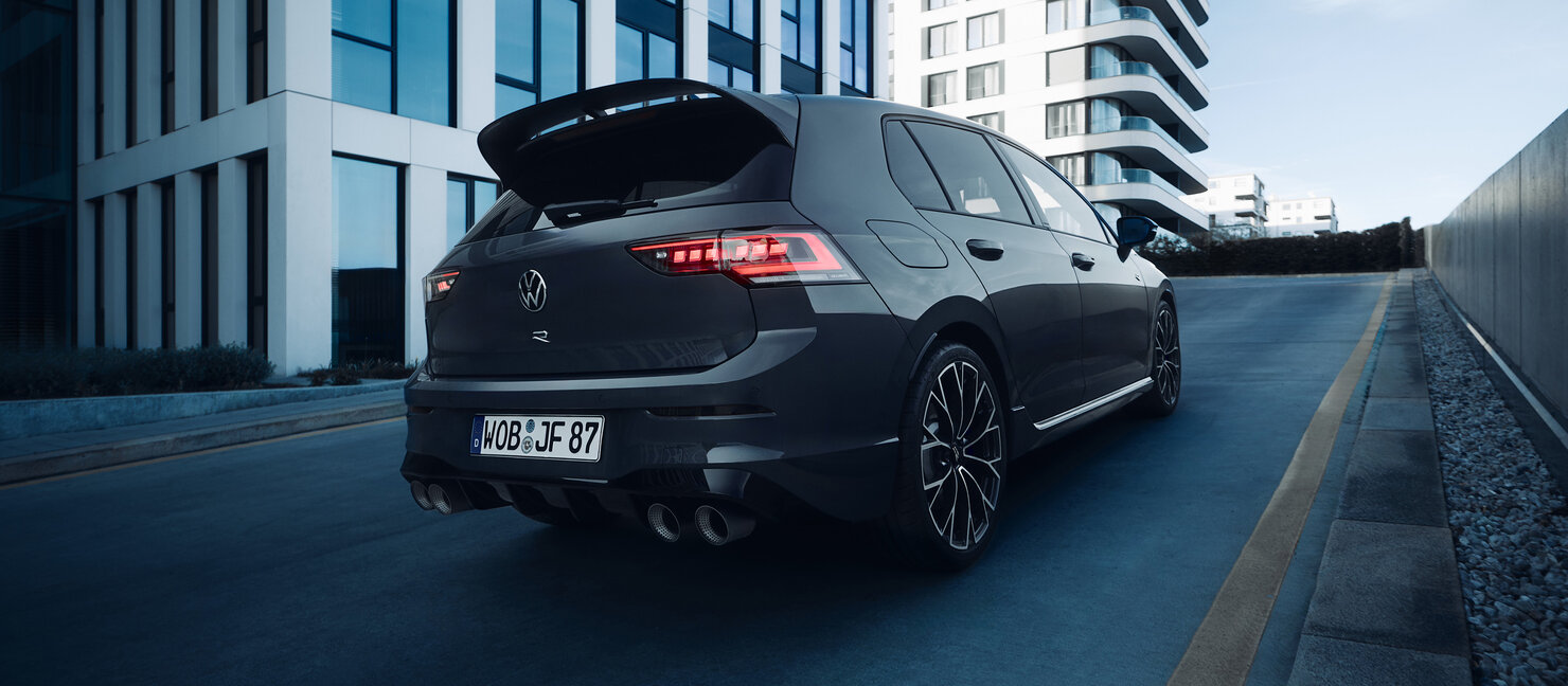 Heckansicht des Volkswagen Golf R mit Dachspoiler, R-Emblem und vier Endrohren auf urbaner Fahrbahn
