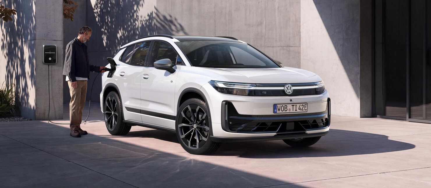Weißer Volkswagen ID. Tiguan in Dreiviertelansicht vor einem Gebäude mit einer Person neben dem Fahrzeug