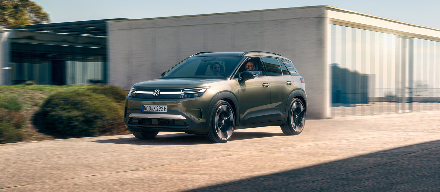 Volkswagen ID. Cross fährt auf einer Straße vor moderner Architektur in Seitenansicht