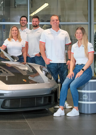 Service-Mitarbeitende des Porsche Zentrums neben einem 911 GT3 RS im Autohaus