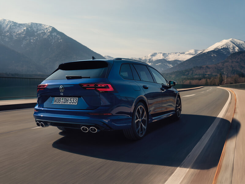 Ein blauer Volkswagen Golf Variant R fährt auf einer kurvigen Bergstraße vor alpiner Landschaft.