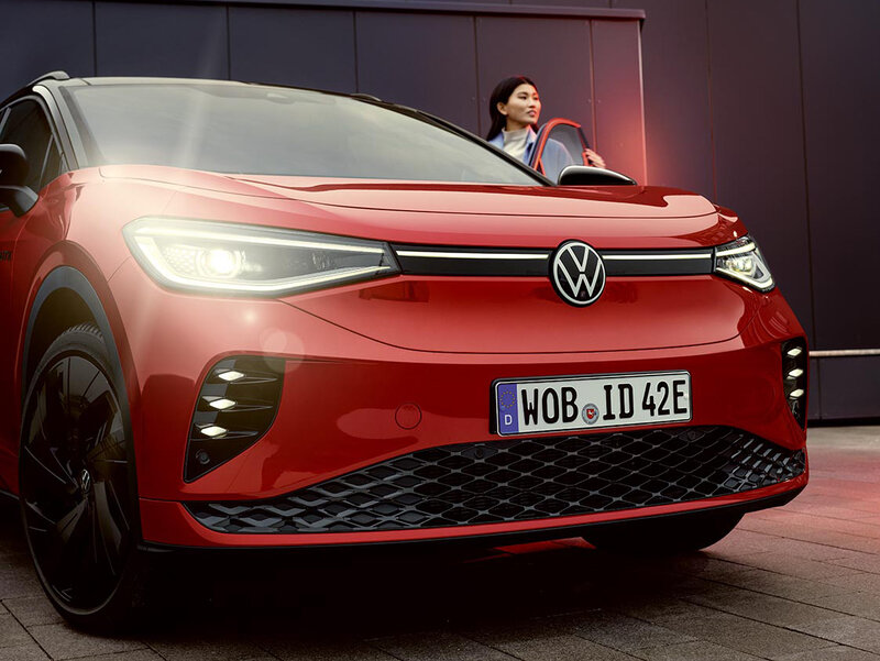 Frontansicht eines roten Volkswagen ID.4 GTX mit beleuchteten LED-Matrix-Scheinwerfern und markanter Frontpartie in urbaner Umgebung.