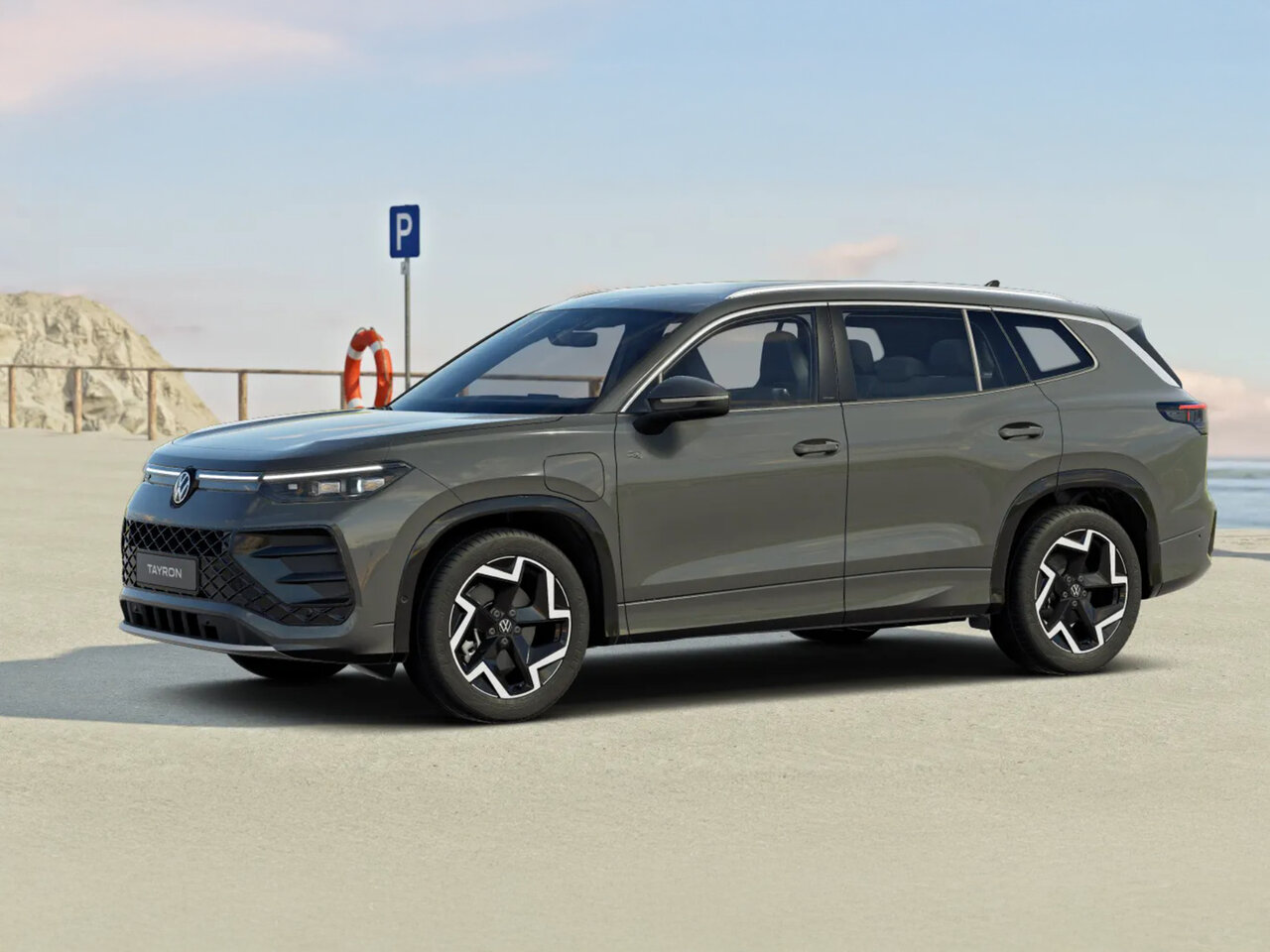 Volkswagen Tayron in Grau steht auf einem Parkplatz nahe der Küste bei klarem Himmel