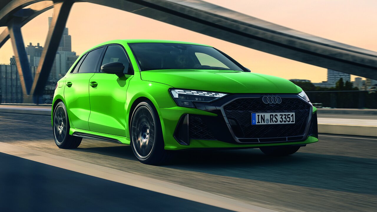 Audi RS3 Sportback in Grün fährt dynamisch über eine Brücke in urbaner Umgebung mit markanter Frontansicht