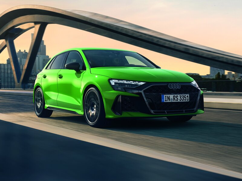 Audi RS 3 Sportback in Grün in dynamischer Fahrszene, mit breitem Stand, RS-Grill und sportlicher Linienführung