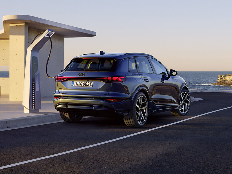 Audi Q6 e-tron an Schnellladesäule mit markantem SUV-Design, breiter Lichtsignatur und kraftvoller Silhouette