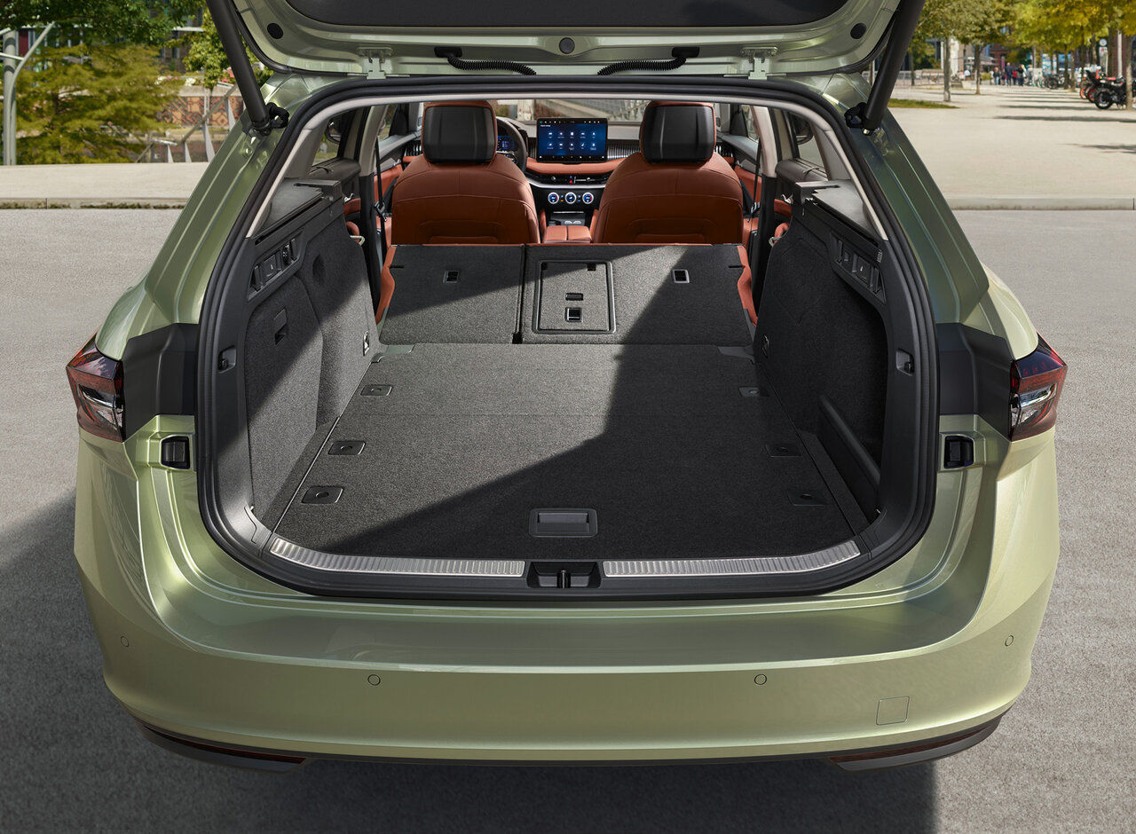 Offener Kofferraum eines Škoda Superb Combi in Ice Tea-Beige Metallic mit umgeklappter Rücksitzbank auf einer Straße bei Tageslicht