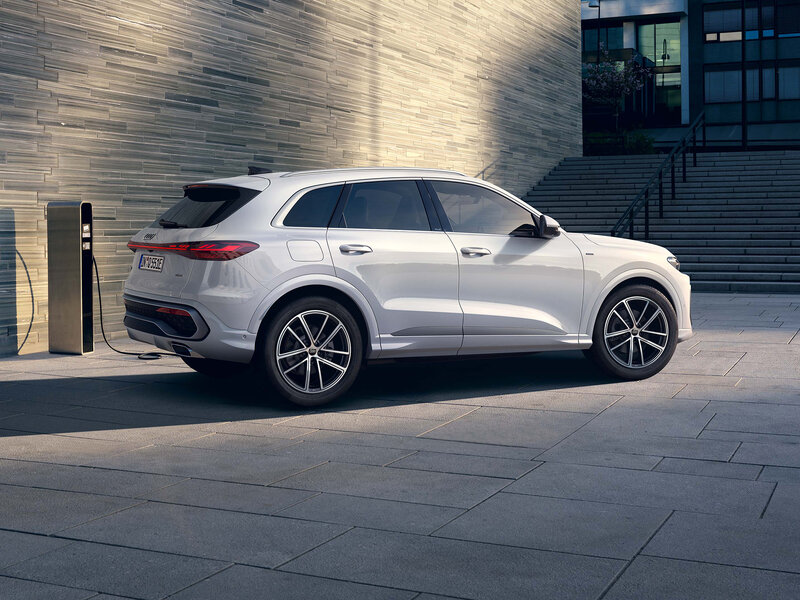 Audi Q5 mit Hybridantrieb in moderner Architekturkulisse, verbindet effiziente Technologie mit hohem Alltagskomfort