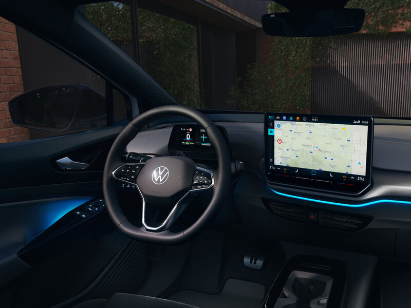 Fahrerplatz des Volkswagen ID.4 bei Dunkelheit mit beleuchtetem Armaturenbrett, Lenkrad und zentralem Infotainmentdisplay.