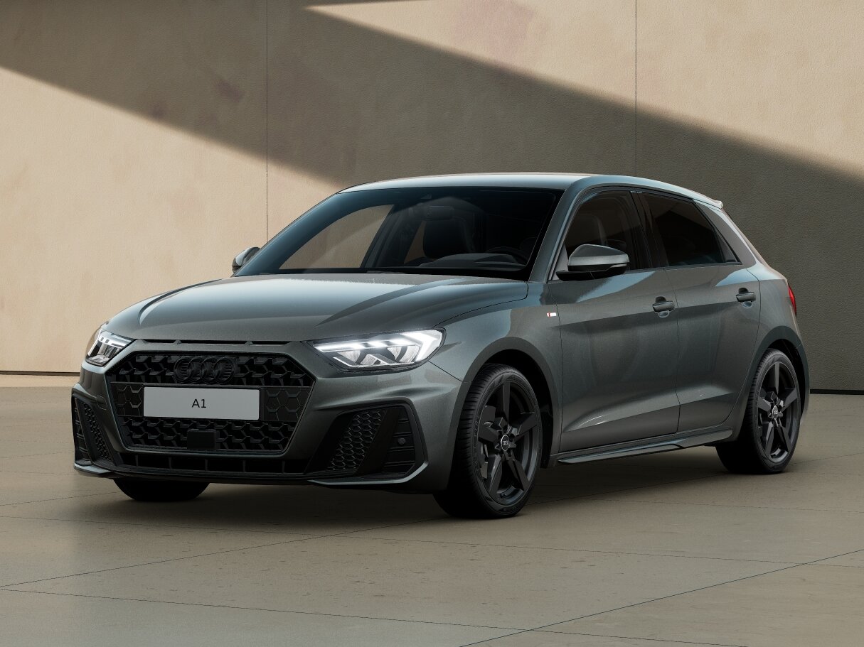 Audi A1 in Frontansicht schräg von vorn vor moderner Architektur mit eingeschaltetem LED-Licht und dunklen Leichtmetallrädern