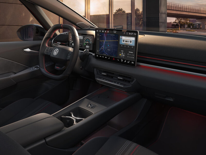 Innenraum des Volkswagen ID.3 GTI mit Multifunktionslenkrad, zentralem Touchscreen, Mittelkonsole und roten Akzenten am Armaturenbrett