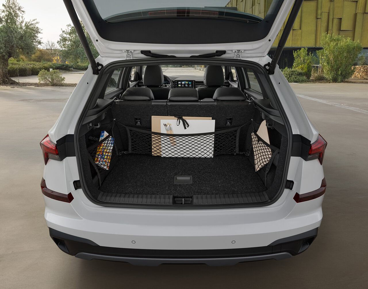 Offener Kofferraum eines Škoda Kamiq in Weiß mit mehreren Paketen auf einer asphaltierten Fläche.