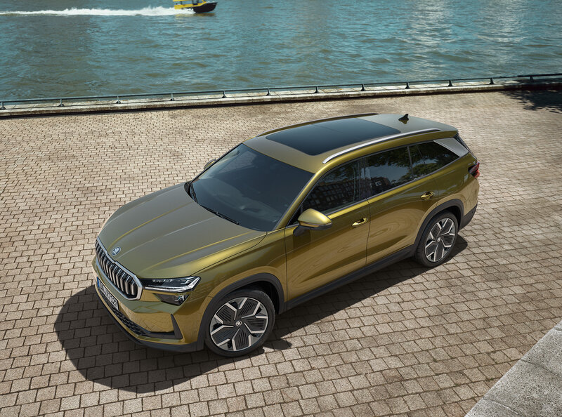 Škoda Kodiaq in Gold-Bronze Metallic steht auf einem gepflasterten Platz am Wasser bei sonnigem Wetter.