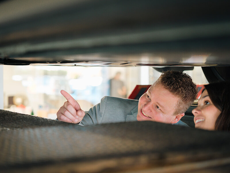 Zwei Personen begutachten in der Volkswagen Werkstatt von Auto Bach in Limburg den Unterboden eines Fahrzeugs auf der Hebebühne