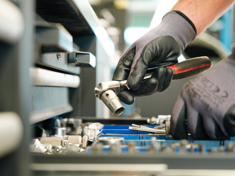 Mechaniker greift in der Volkswagen Werkstatt von Auto Bach in Limburg mit Handschuhen nach einem Werkzeug in einer Werkbankschublade