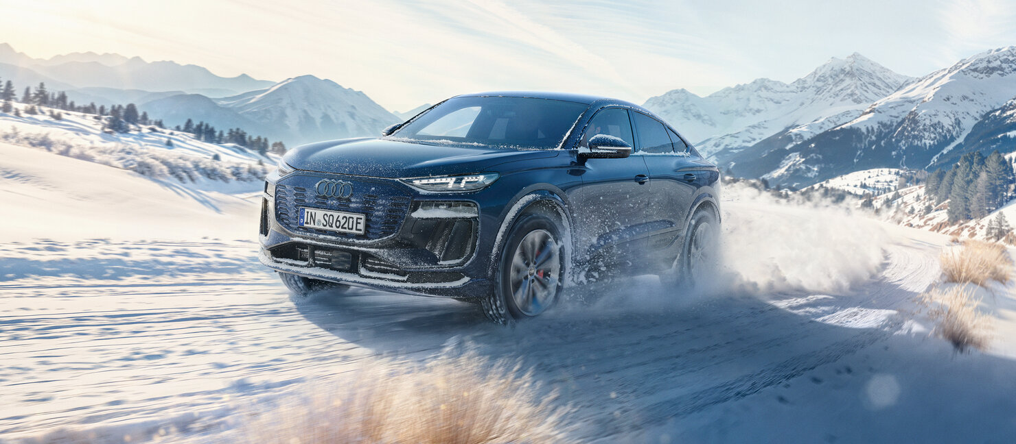 Audi SQ6 Sportback in winterlicher Berglandschaft unterwegs, mit starkem Schneewirbel hinter dem Fahrzeug