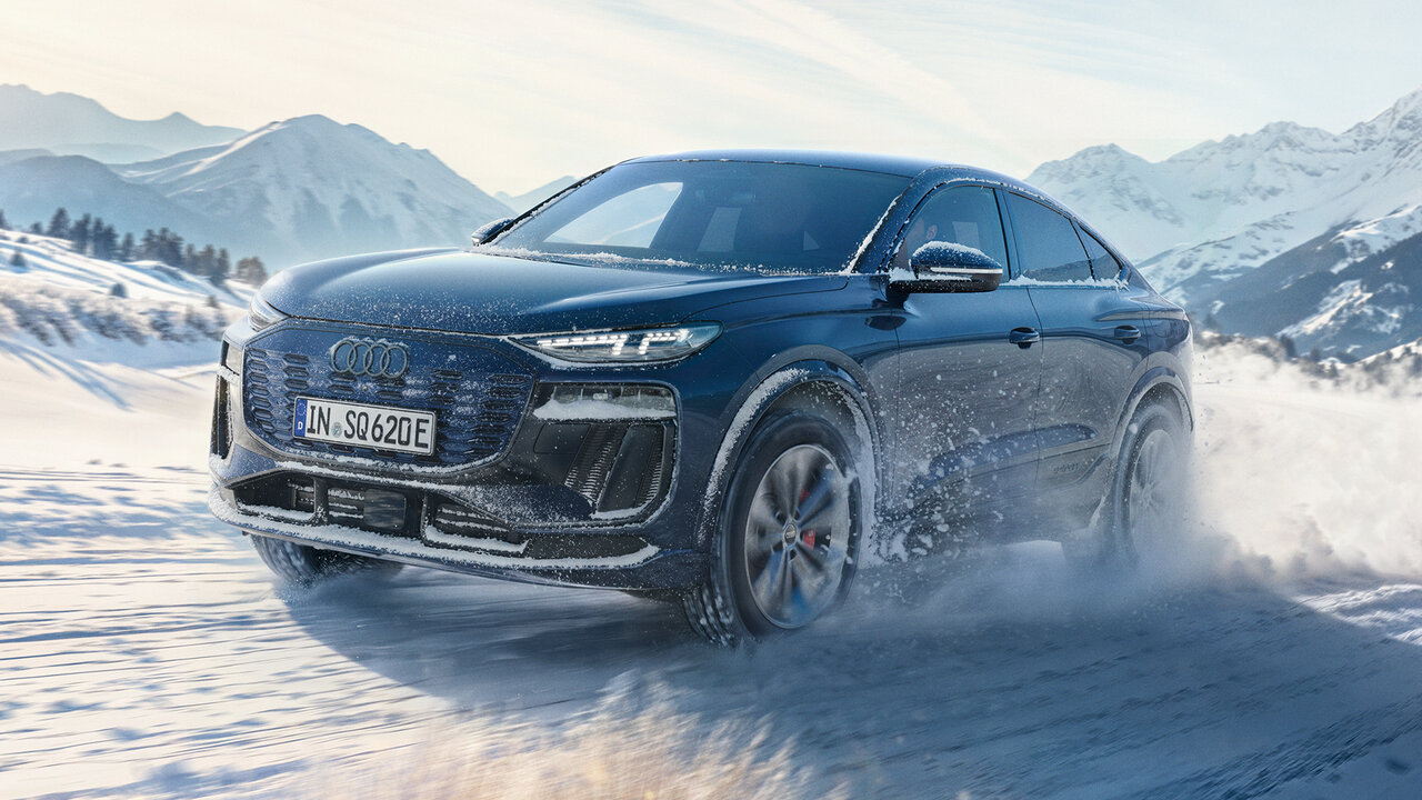 Schwarzer Audi SQ6 Sportback fährt dynamisch durch verschneite Landschaft und wirbelt Schnee auf