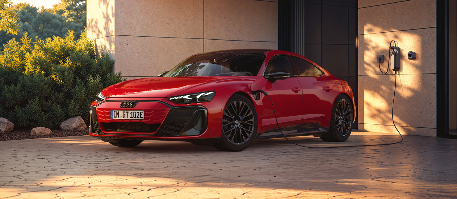 Audi e-tron GT an einer Ladestation vor Wohngebäude, elegante Linienführung, flaches Dach und markante LED-Lichtsignatur