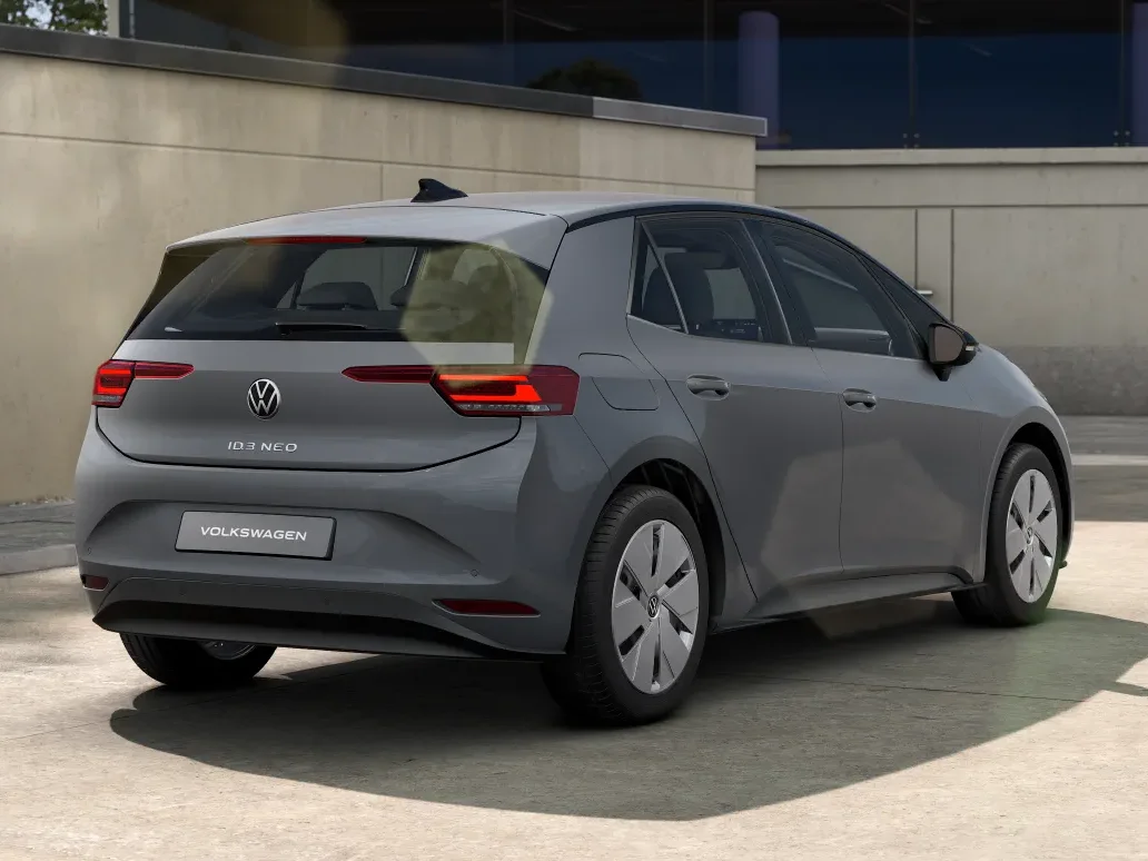 Grauer Volkswagen ID.3 Neo Trend steht auf einer hellen Fläche mit einem Haus als Hintergrund