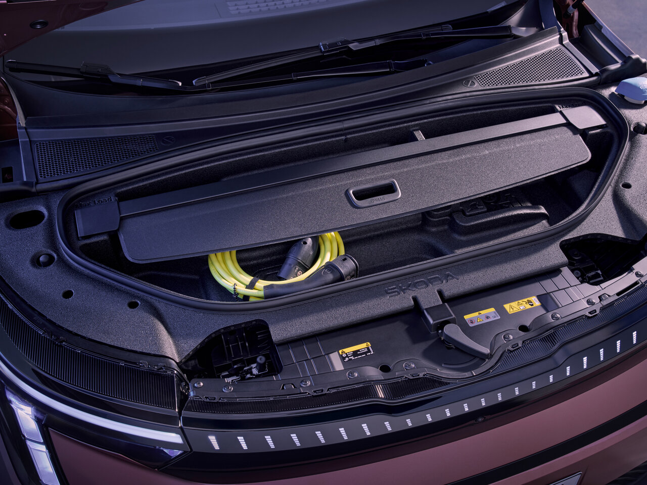Geöffneter Frontstauraum des neuen vollelektrischen Škoda Peaq mit Ladekabel unter der Motorhaube.