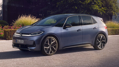 Volkswagen ID.3 Neo in Seitenansicht geparkt am Straßenrand vor bepflanzter Grünfläche bei Abendlicht