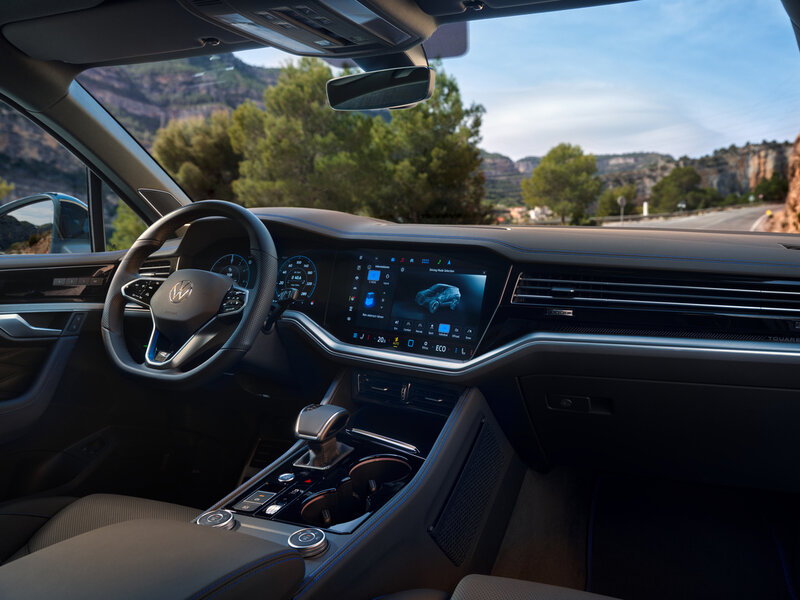 Innenansicht eines Volkswagen Touareg R eHybrid mit digitalem Cockpit, großem Infotainmentdisplay und Mittelkonsole.