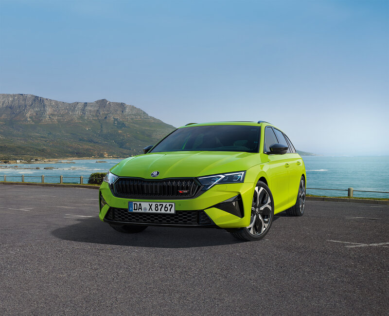 Škoda Octavia RS in Mamba-Grün steht auf einem Parkplatz mit Blick auf Meer und Berge bei klarem Himmel