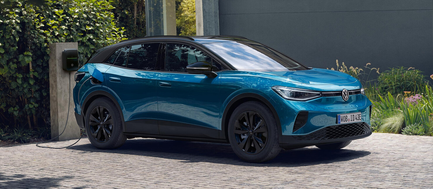 Volkswagen ID.4 in Blau lädt an einer heimischen Wallbox vor einem Haus