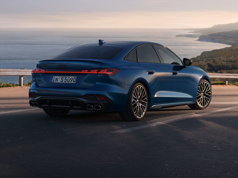 Audi S5 Limousine in dynamischer Heckansicht an Küstenstraße mit fließender Linienführung und sportlicher Präsenz
