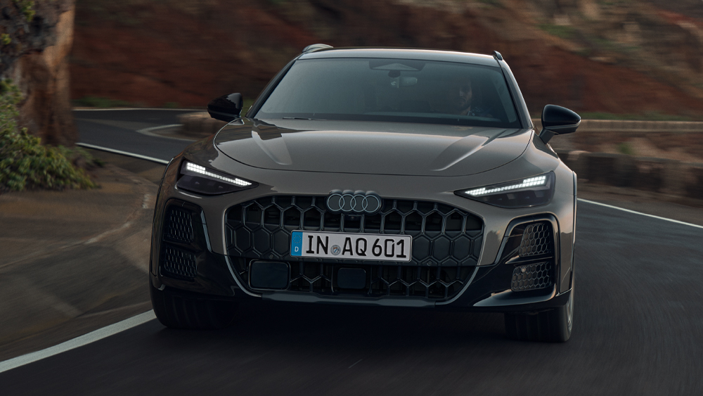 Audi A6 allroad in Frontansicht auf kurviger Küstenstraße vor Felslandschaft während der Fahrt bei natürlichem Tageslicht