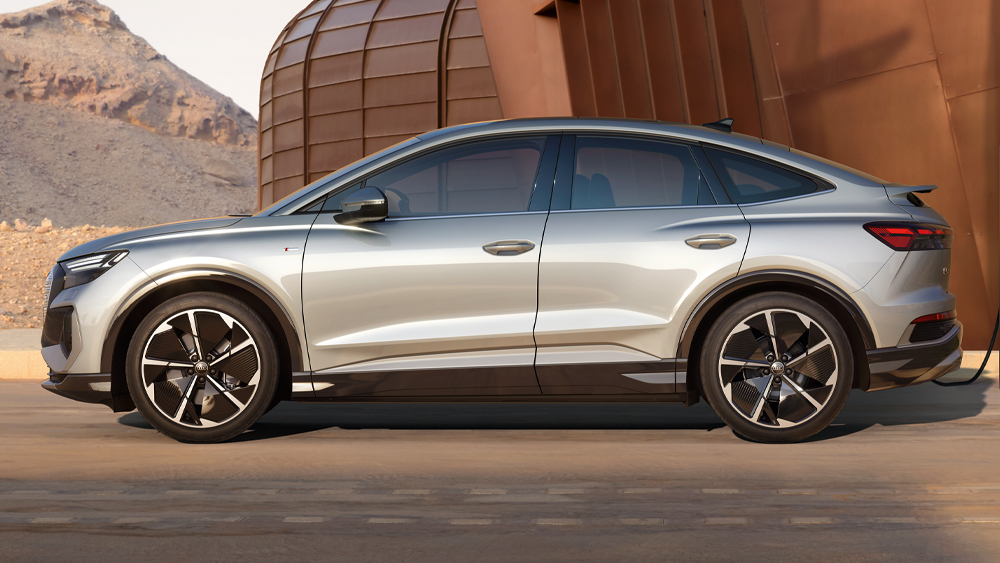 Audi Q4 Sportback e-tron in seitlicher Ansicht mit coupéhafter Dachlinie, großen Leichtmetallrädern und klarer Lichtgrafik