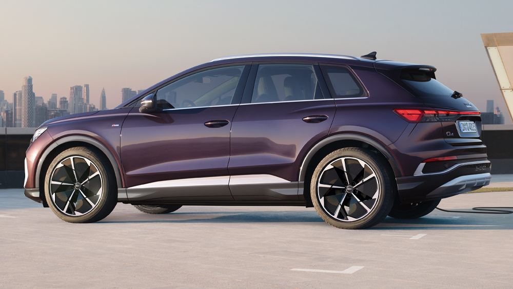 Audi Q4 e-tron in Seitenansicht auf offenem Parkdeck, dunkelviolette Lackierung und markante SUV-Proportionen