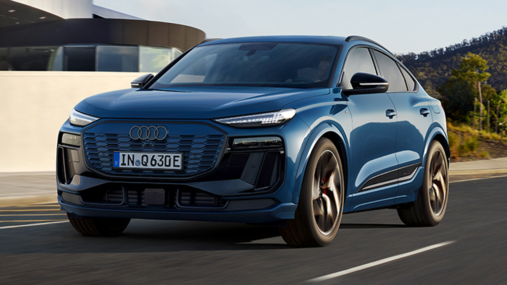 Audi Q6 e-tron fährt auf Straße entlang der Küste, markantes SUV-Design mit breitem Singleframe-Grill und LED-Lichtsignatur