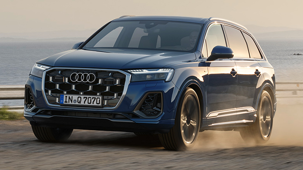 Blauer Audi Q7 fährt dynamisch an der Küste entlang, aufgewirbelter Staub betont seine kraftvolle Präsenz