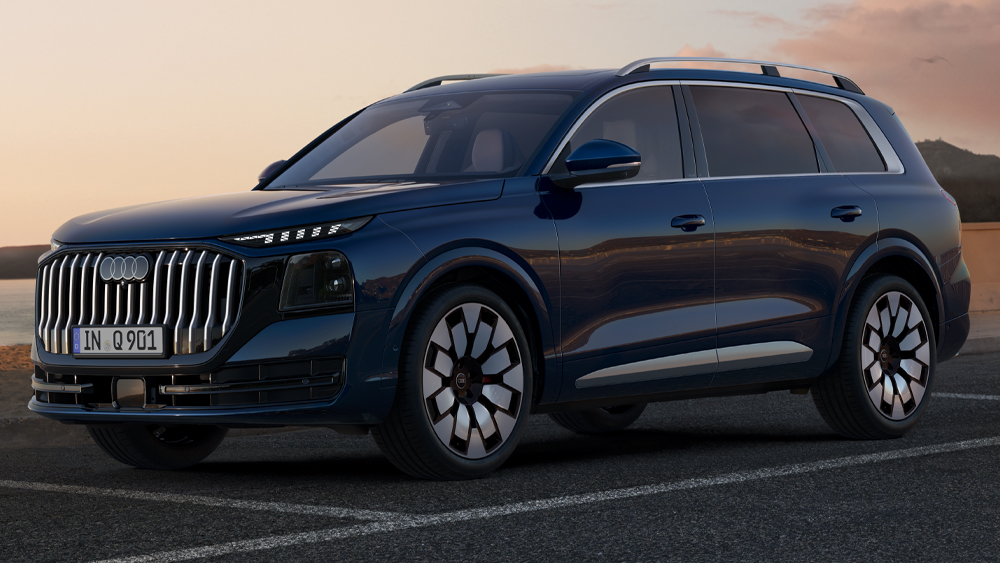 Audi Q9 in Dunkelblau aus Frontseitenperspektive auf einer Straße bei Sonnenuntergang mit markantem Kühlergrill und großen Leichtmetallrädern