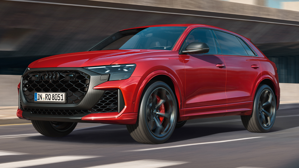 Audi RS Q8 in Rot fährt dynamisch auf der Straße, sportliche Front mit großen Lufteinlässen und schwarzen RS-Felgen